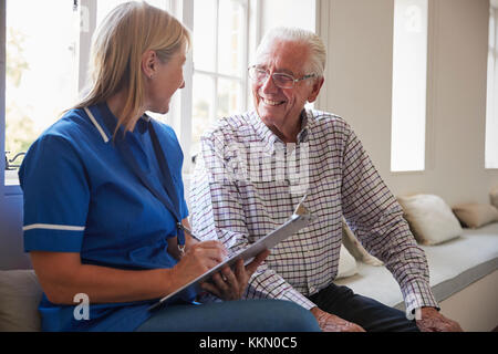 Senior man sits with nurse making notes at retirement home Stock Photo