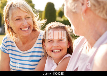 Three female generations of family sitting in a garden Stock Photo