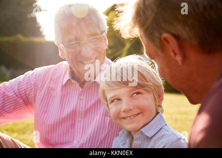 Three male generations of a family sitting in a garden Stock Photo