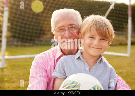 Senior man and grandson holding ball smiling at camera Stock Photo