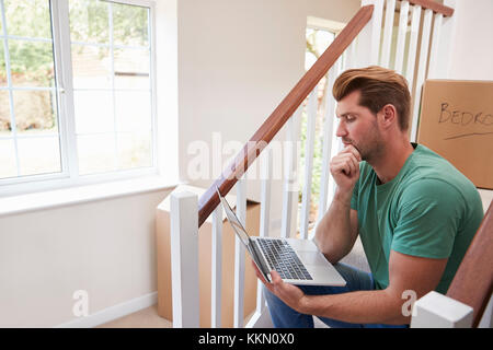Man Moving Into New Home Looking At Personal Finances On Laptop Stock Photo