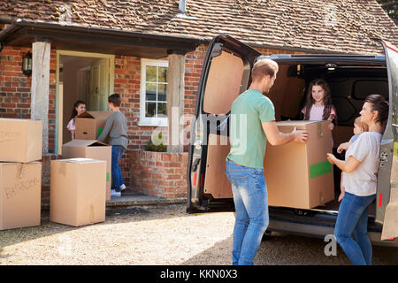 Family Unloading Boxes From Removal Truck On Moving Day Stock Photo