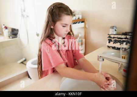 Girl Washing Hands In Bathroom Basin At Home Stock Photo