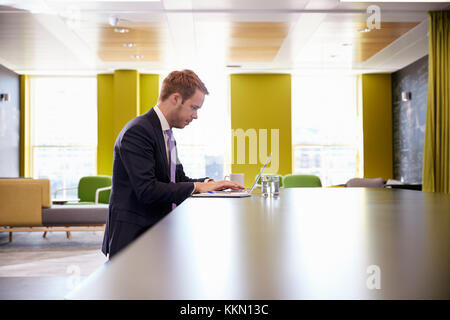Young businessman working on a laptop in office meeting area Stock Photo