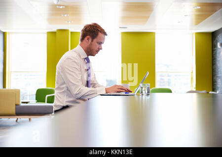 Businessman using laptop in an office meeting area Stock Photo