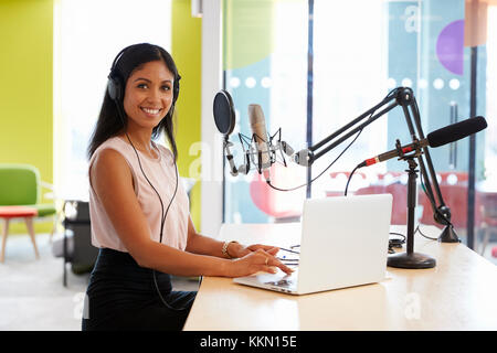 Young mixed race woman recording a podcast smiling to camera Stock Photo