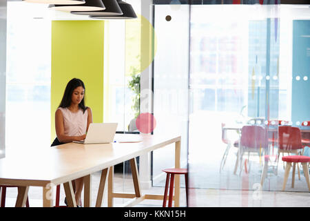 Young black woman working alone in an office meeting area Stock Photo