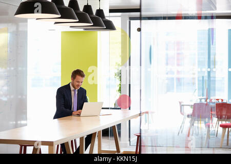 Young white man working alone in an office meeting area Stock Photo
