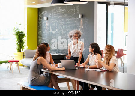 Female boss addressing her colleagues at an informal meeting Stock Photo