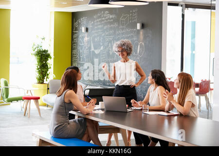 Female boss standing at an informal team meeting Stock Photo