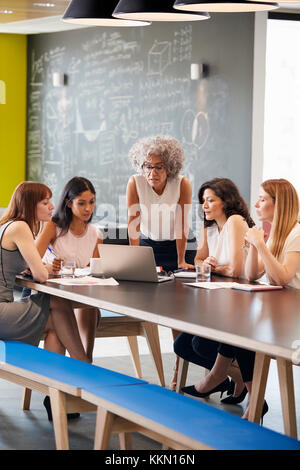 Female work colleagues using laptop computer in a meeting Stock Photo