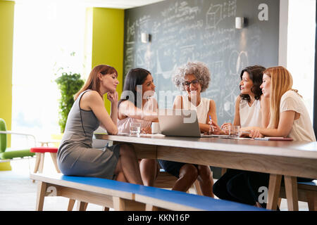 Female work colleagues using laptop in an informal meeting Stock Photo