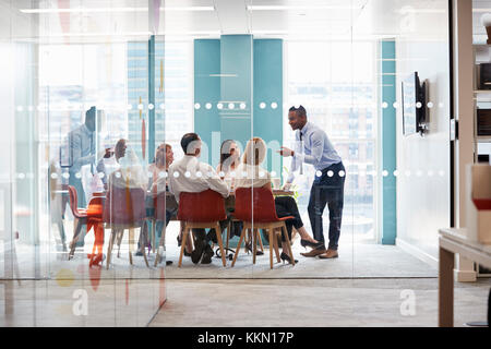 Young male boss stands leaning on table at business meeting Stock Photo