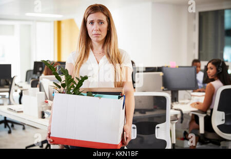 Fired female employee holding box of belongings in an office Stock Photo