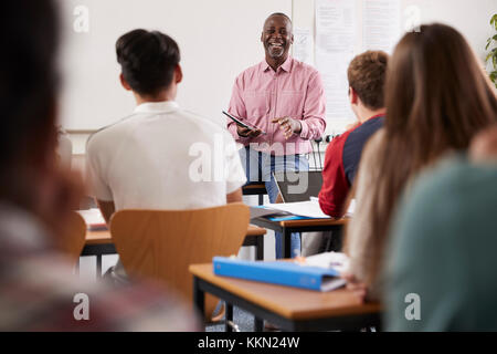 Male College Tutor With Digital Tablet Teaching Class Stock Photo