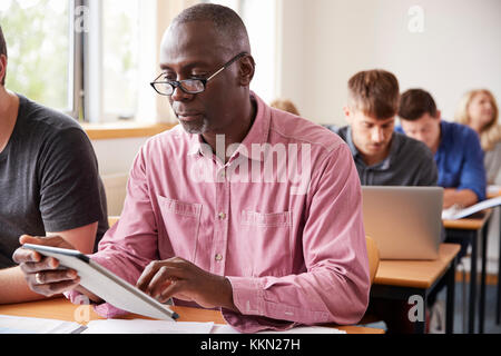 Mature Student Using Digital Tablet In Adult Education Class Stock Photo