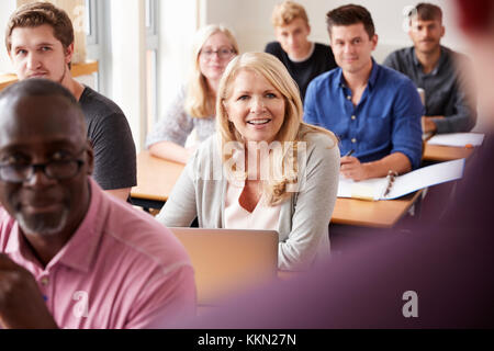 Male Tutor Teaching Class Of Mature Students Viewed From Behind Stock Photo