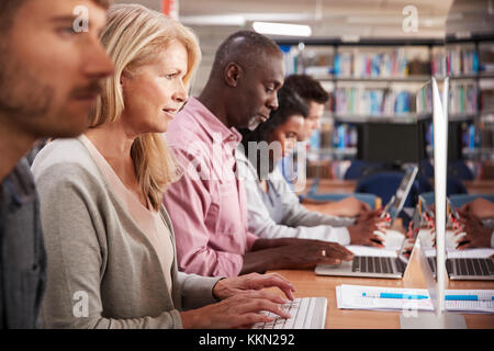 Group Of Mature College Students Working On Computers In Library Stock Photo