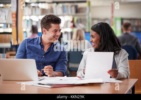 Two Mature Students Working On Laptop In College Library Together Stock Photo