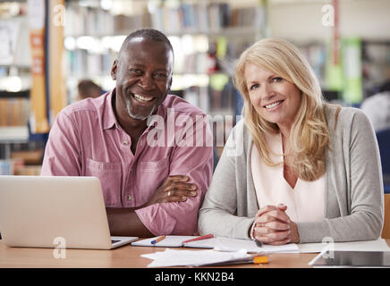 Portrait Of Two Mature Students Working In College Library Stock Photo