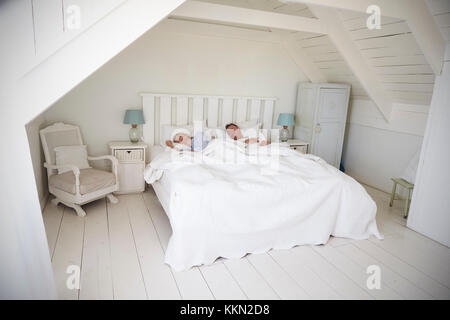 Couple Sleeping In Light And Airy White Bedroom Stock Photo