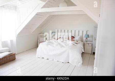 Couple Sleeping In Light And Airy White Bedroom Stock Photo