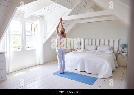 Woman At Home Starting Morning With Yoga Exercises In Bedroom Stock Photo