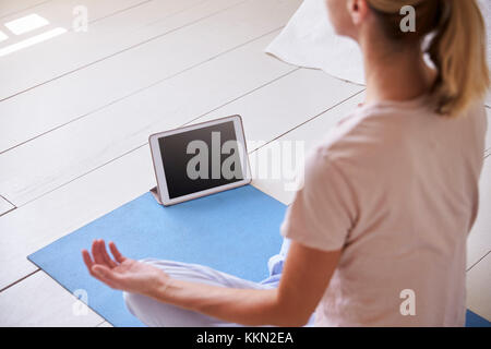 Woman With Digital Tablet Using Meditation App In Bedroom Stock Photo