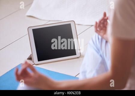 Woman With Digital Tablet Using Meditation App In Bedroom Stock Photo