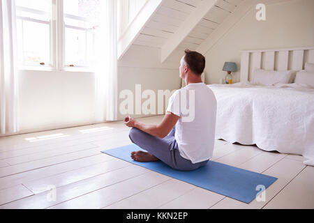 Mature Man With Digital Tablet Using Meditation App In Bedroom Stock Photo