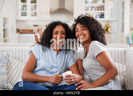 Portrait Of Mother Sitting With Teenage Daughter On Sofa Stock Photo