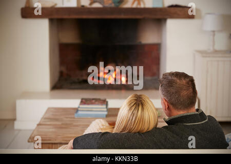 Romantic Couple Relaxing In Lounge Next To Open Fire Stock Photo