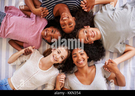 Overhead View Of Teenage Friends Lying On Bed Together Stock Photo
