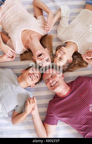 Overhead View Of Family With Teenage Children Lying On Bed