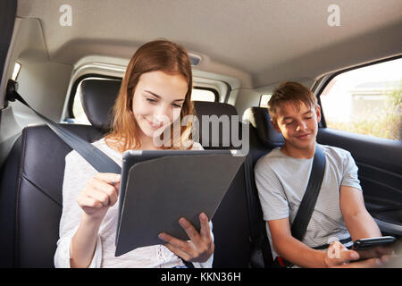 Teenage Children Using Digital Devices On Family Road Trip Stock Photo