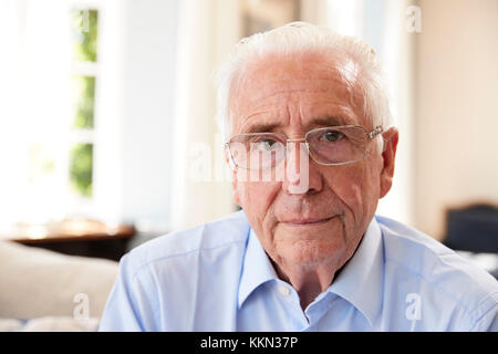 Portrait Of Senior Man Sitting On Sofa Suffering From Depression Stock Photo