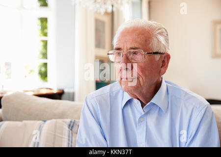 Senior Man Sitting On Sofa At Home Suffering From Depression Stock Photo