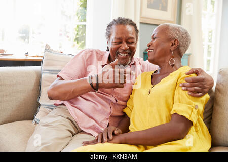 Smiling Senior Couple Sitting On Sofa At Home Together Stock Photo