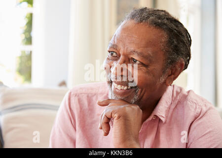 Smiling Senior Man Sitting On Sofa At Home Stock Photo
