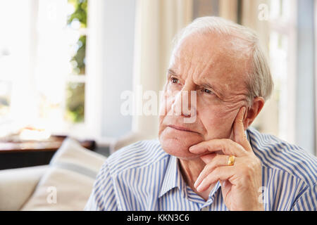 Senior Man Sitting On Sofa At Home Suffering From Depression Stock Photo