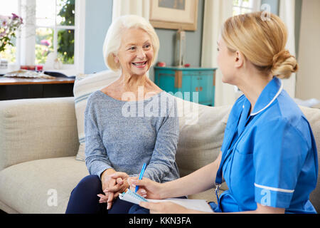 Female Community Nurse Visits Senior Woman At Home Stock Photo