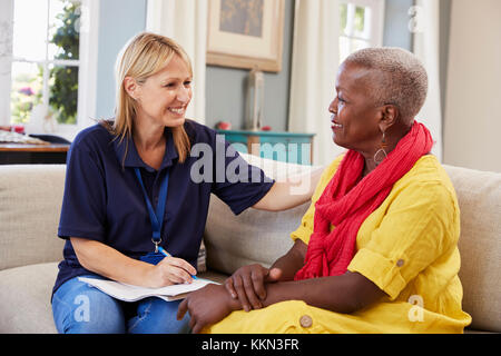 Female Support Worker Visits Senior Woman At Home Stock Photo