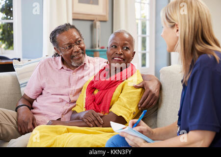Female Support Worker Visits Senior Couple At Home Stock Photo