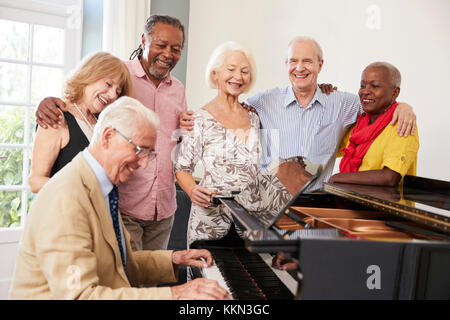 Group Of Seniors Standing By Piano And Singing Together Stock Photo