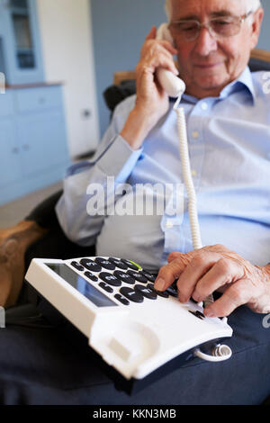 Senior Man At Home Using Telephone With Over Sized Keys Stock Photo