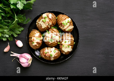 Baked stuffed potatoes with bacon, green onion and cheese on black background with copy space. Top view, flat lay. Stock Photo