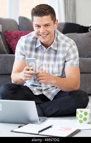 Portrait Of Male Freelance Worker Using Mobile Phone At Home Stock Photo