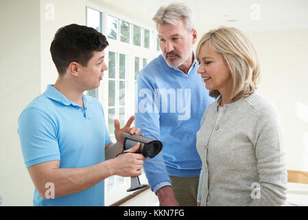 Security Consultant Demonstrating Alarm System To Mature Couple Stock Photo