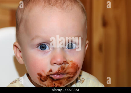 Portrait of a child in the highchair. His face and hands smeared with chocolate Stock Photo