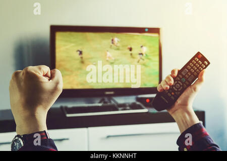 Goal. Man watching football match on television at home. remote control in hand. football fan watches world Cup soccer and more for your favorite foot Stock Photo